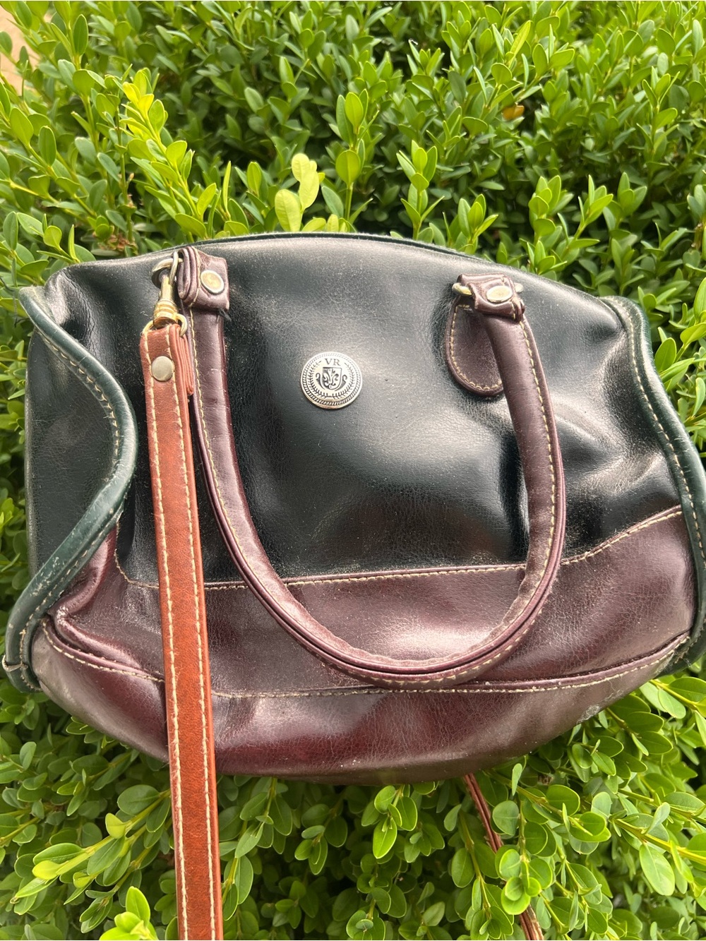 A two-tone leather handbag by Mouflon with a decorative crest emblem.